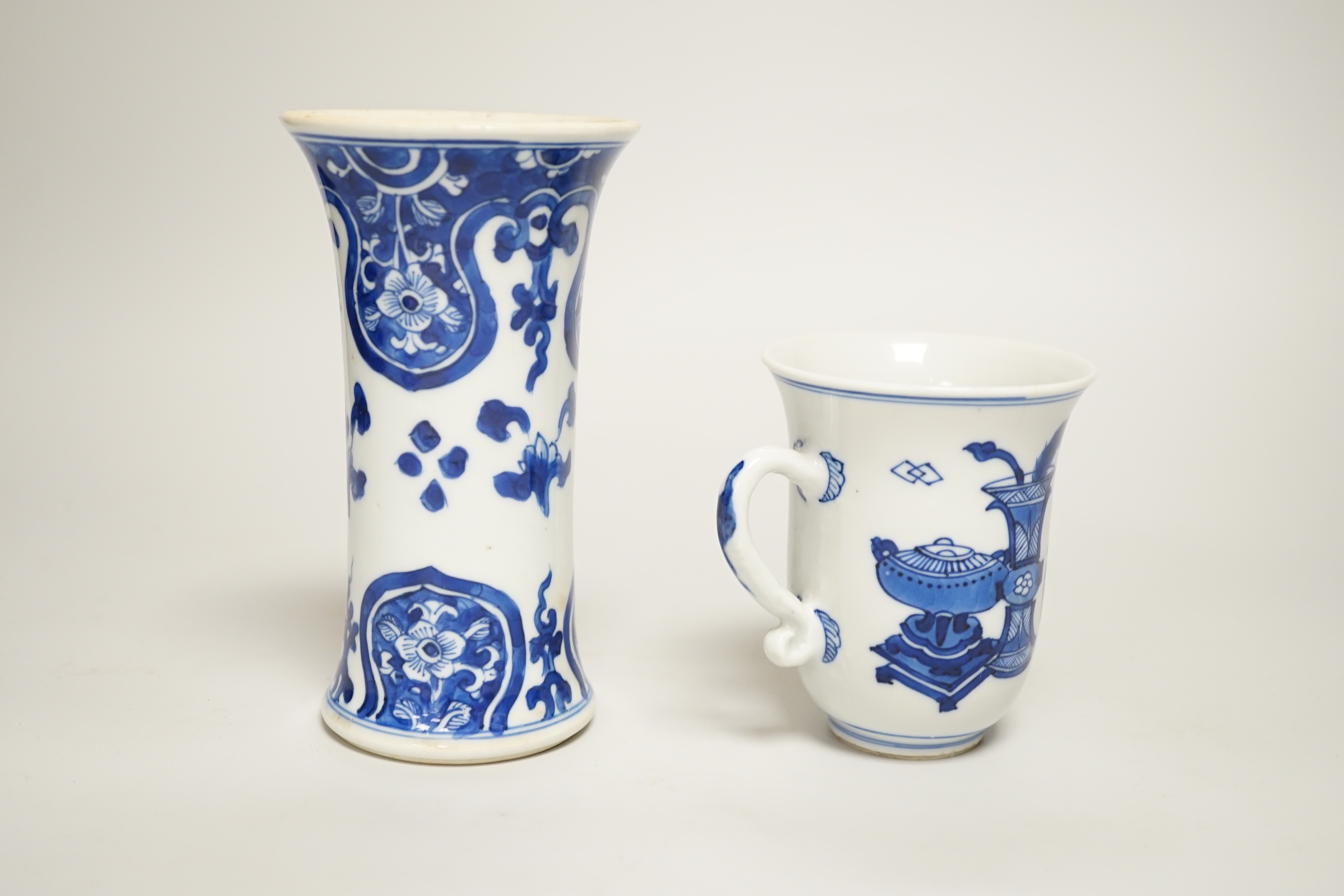 A Chinese blue and white small vase and a similar ‘Hundred Antiques’ chocolate cup, both Kangxi period, chocolate cup 9cms high